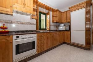 uma cozinha com armários de madeira e um forno de fogão branco em Casa rural de uso turístico Playa de Carnota em Canedó