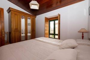 um quarto com uma grande cama branca e uma janela em Casa rural de uso turístico Playa de Carnota em Canedó