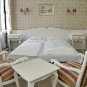 a bedroom with two white beds and two chairs at Fiume Hotel in Békéscsaba