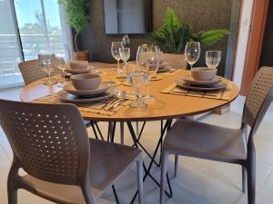 een eettafel met stoelen en een tafel met wijnglazen bij Villa Kamby 101B Milagres , ao lado da Capela dos Milagres in São Miguel dos Milagres