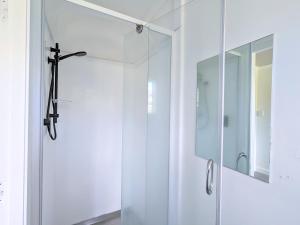 a glass shower door in a bathroom with a mirror at 4 Bedrooms Escape, close to CBD in Rotorua +37 photos
