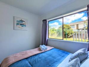 ein Schlafzimmer mit einem Bett und einem großen Fenster in der Unterkunft 4 Bedrooms Escape, close to CBD in Rotorua