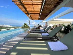 a row of chaise lounge chairs on a swimming pool at Dominique By Stay Q in Cartagena de Indias