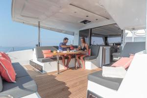 Ein Mann und eine Frau sitzen an einem Tisch auf einer Yacht. in der Unterkunft catamarano isla 40 in San Vincenzo