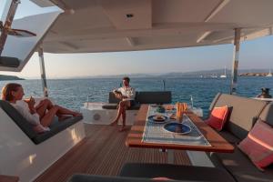 a man and two women sitting on the back of a boat at catamarano isla 40 in San Vincenzo