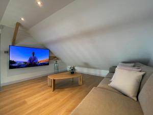 uma sala de estar com um sofá e uma televisão na parede em Chez Gaston - Entrelacs 