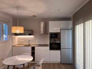 a kitchen with white cabinets and a table and a white refrigerator at Loft luxury Mirador in Cádiz