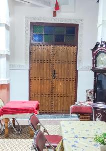 um quarto com uma porta e cadeiras de madeira e um relógio em Fes Hostel Zaouia em Fez