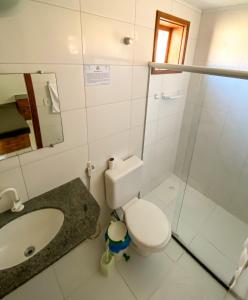 uma casa de banho com um lavatório, um WC e um espelho. em Residencial Malibu em Porto Seguro