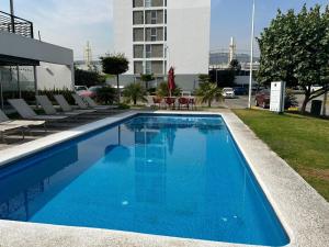 a blue swimming pool with chairs and a building at Luxurious Apartment Bardeen New Port Beach 1 Bedroom in Irvine