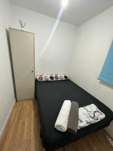 sypialnia z czarnym łóżkiem i białą ścianą w obiekcie Fast Single Rooms w Madrycie