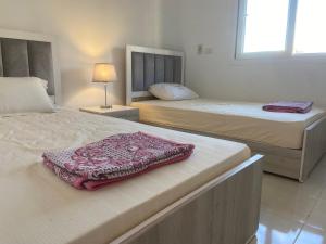 a bedroom with two beds and a blanket on top at Luxury Inn: 3BR Amazing Garden View in Madinaty B6 in Madinaty +28 photos
