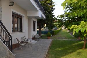 patio z krzesłami i stołami na domu w obiekcie Cozy Garden House w mieście Árgos Orestikón