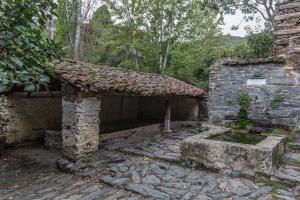 un antiguo edificio de piedra con techo en un patio en El Mirador de Las Jaras en Patones