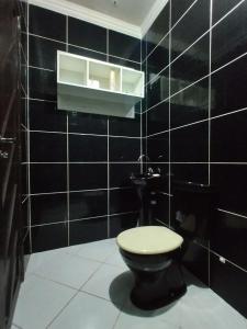 a bathroom with a toilet and a black tiled wall at Casa de Praia em Pirangi in Nísia Floresta