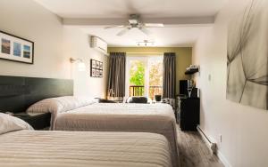 a hotel room with two beds and a window at Hôtel Motel Le Beluga in Tadoussac