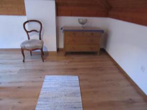 a room with a chair and a dresser and a rug at Maisonette in Biasca