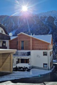 a house with the sun shining on the mountain at Chasa Siringia EG in Samnaun - Laret