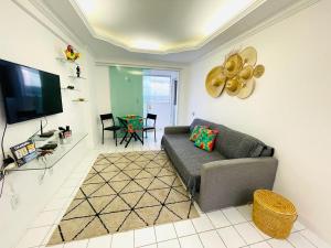 uma sala de estar com um sofá e uma televisão de ecrã plano em FLAT 13º andar COM VISTA PARA MARagogi em São José da Coroa Grande