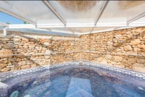 una gran piscina con una pared de piedra en CASA RÚSTICA EN MAS ENFABONA, en Els Ibarsos