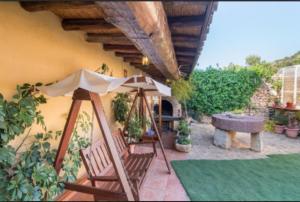 un patio con sombrilla, sillas y mesa en CASA RÚSTICA EN MAS ENFABONA, en Els Ibarsos