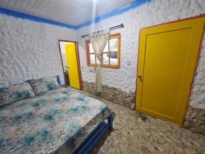 um quarto com uma cama e uma porta amarela em Baru sunset em Barú