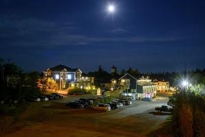 un groupe de maisons avec des voitures garées sur un parking la nuit dans l'établissement Hôtel Motel Le Beluga, à Tadoussac