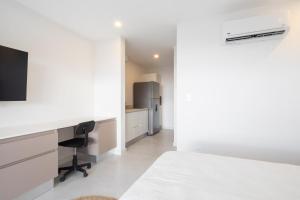 1 dormitorio con cama, escritorio y nevera en AYLA C - new, cozy Ocean view Studio in Flamingo en Playa Flamingo