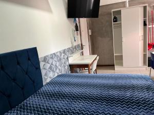 - une chambre avec un lit bleu et un bureau dans l'établissement STUDIO 203 | WIFI 600MB | RESIDENCIAL JC, um lugar para ficar., à Belém