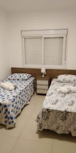 two beds sitting in a room with a window at Apartamento Confortável em Capão in Capão da Canoa +13 photos