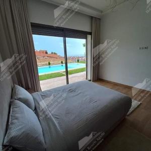 - une chambre avec un grand lit et une grande fenêtre dans l'établissement Nostalgic Nirvana Villa Taghazout Bay ocean & mountain view, à Taghazout