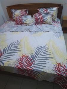 Una cama con colcha con hojas de palmera. en The furnished residences of Fasso Kanu -villa en Bamako