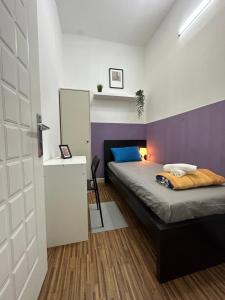 ein Schlafzimmer mit einem Bett und einer lila Wand in der Unterkunft Prime Partition Room in Al Barsha 1 Near Metro in Dubai