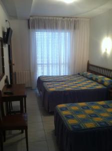 a hotel room with two beds and a desk and a window at Hotel Pipo in A Lanzada +12 photos