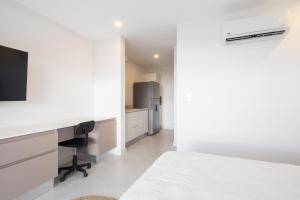 1 dormitorio con cama, escritorio y nevera en AYLA D - lovely Ocean view Studio in Flamingo en Playa Flamingo