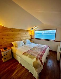 um quarto com uma cama grande e uma janela grande em Weskar Lodge Hotel em Puerto Natales