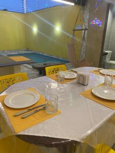 a table with white plates and yellow napkins on it at CASA ATALAIA 2 SUITES Salinopolis in Salinópolis