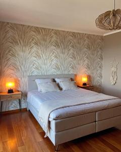a bedroom with a large bed with two lamps on tables at Casa do Mundo Madeira in Gaula