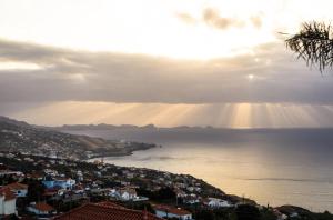 een uitzicht op de oceaan met de zon op het water bij Casa do Mundo Madeira in Gaula