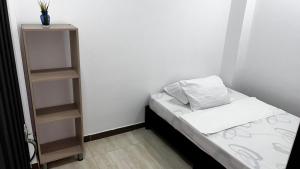 um pequeno quarto com uma cama e uma estante de livros em EL EDÉN 102 em Puerto Triunfo