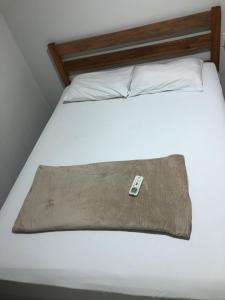 a bed with a pillow with a remote control on it at Hotel Casa Branca in Garanhuns