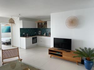 a living room with a tv and a kitchen at Face à la mer in Le Gosier