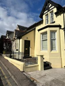 a white house with a black door and a fence at 4 Caberfeidh in Fort William