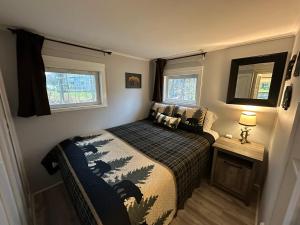 a small bedroom with a bed and two windows at Escape to a Streamside Cabin in the Lower Catskills in Wurtsboro