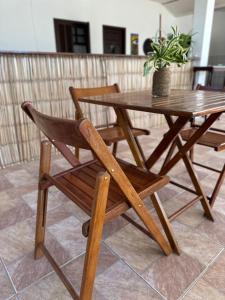 Pousada Mawe في باراتي: طاولة وكرسي خشبي مع نبات خزاف عليه