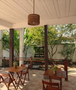Pousada Mawe في باراتي: طاولتين خشبتين وكراسي على فناء به أشجار