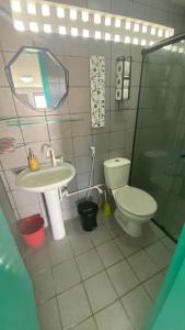 a bathroom with a sink and a toilet and a mirror at Onda Colorida - Praia de Serrambi CASA 2 - VERDE in Porto De Galinhas