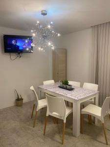 uma mesa de jantar com cadeiras brancas e um lustre em Carlos Paz-Lake Towers em Villa Carlos Paz