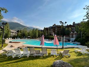 einen Pool mit Stühlen und Sonnenschirmen in einem Resort in der Unterkunft Perfect Ski or Bike in-out Hot Tub Pool in Panorama