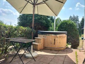 einen Picknicktisch mit einem Sonnenschirm neben einem Whirlpool in der Unterkunft Gîte La Rose Jacuzzi Nordique in La Petite-Pierre